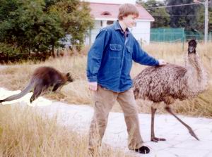 Shannon at the Haicang Safari Park, playing with an emu, and a kangaroo in the background